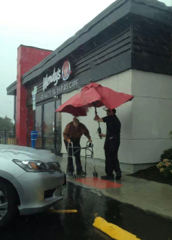 Wendy's Restaurant Wendy's Restaurant outside raining employee holding red umbrella for man with a walker
